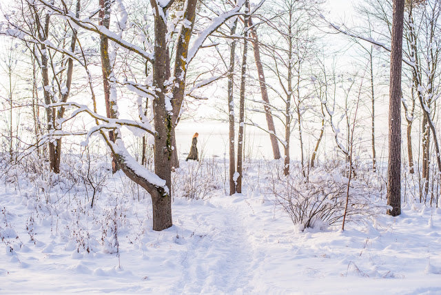 Woman walking in snow covered forest